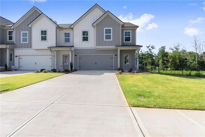 Contemporary multi-story exterior with board and batten siding, attached garages, and a concrete driveway