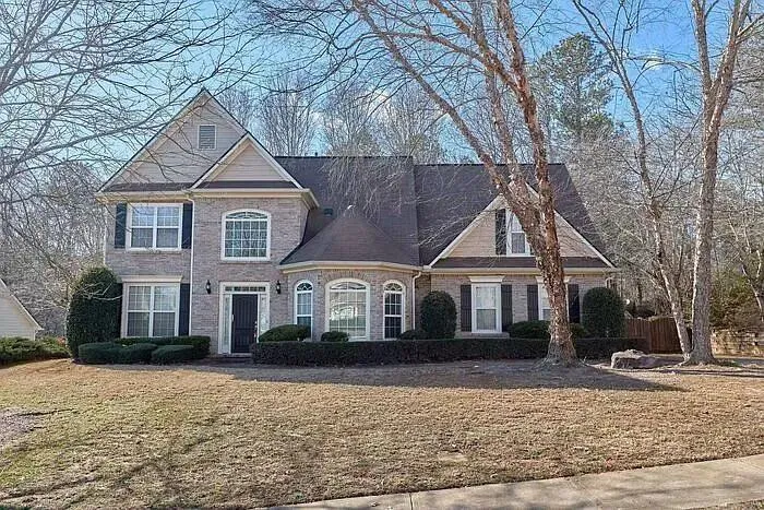 Brick facade with decorative shutters, arched windows, and a prominent front door