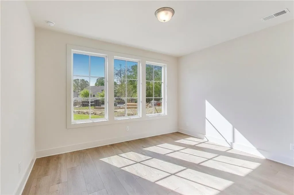 Spare room featuring visible vents, baseboards, and wood finished floors