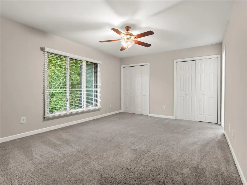 Unfurnished bedroom featuring multiple closets, carpet, and ceiling fan