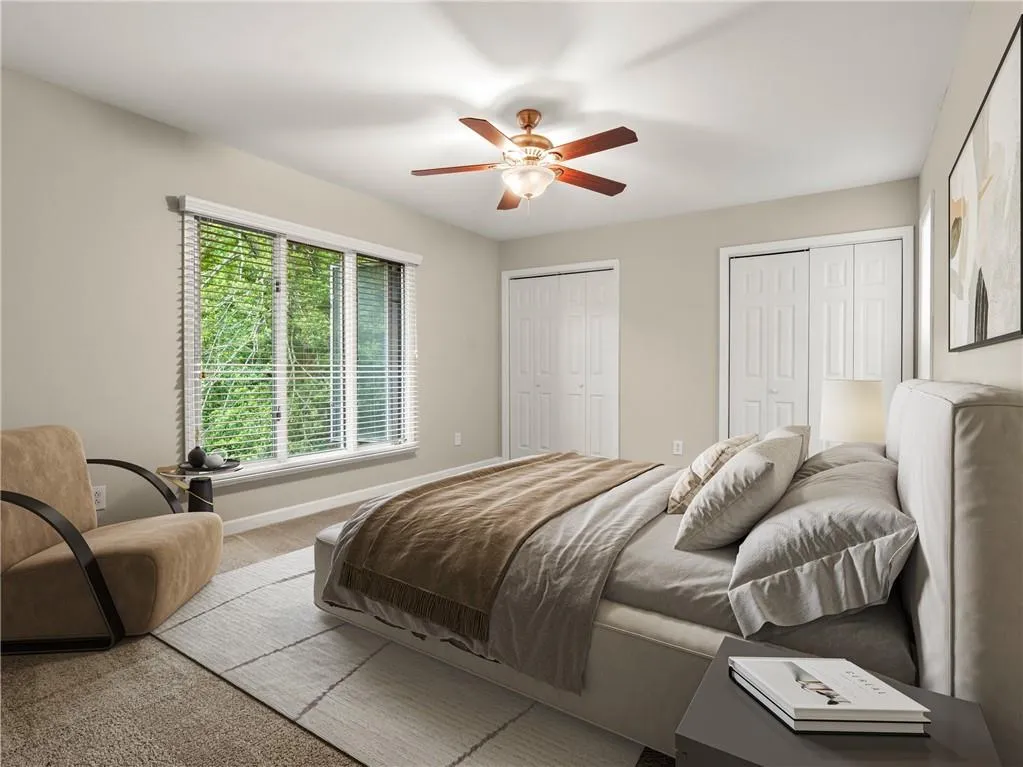 Carpeted bedroom with multiple closets and a ceiling fan