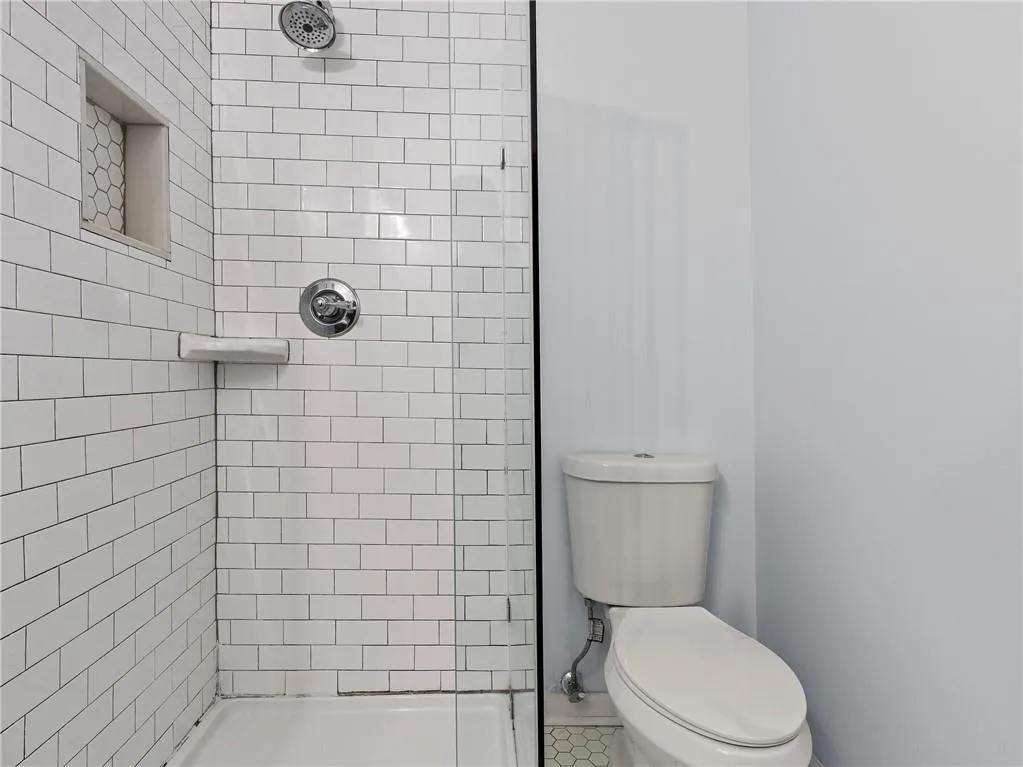 Bathroom featuring a tile shower and toilet