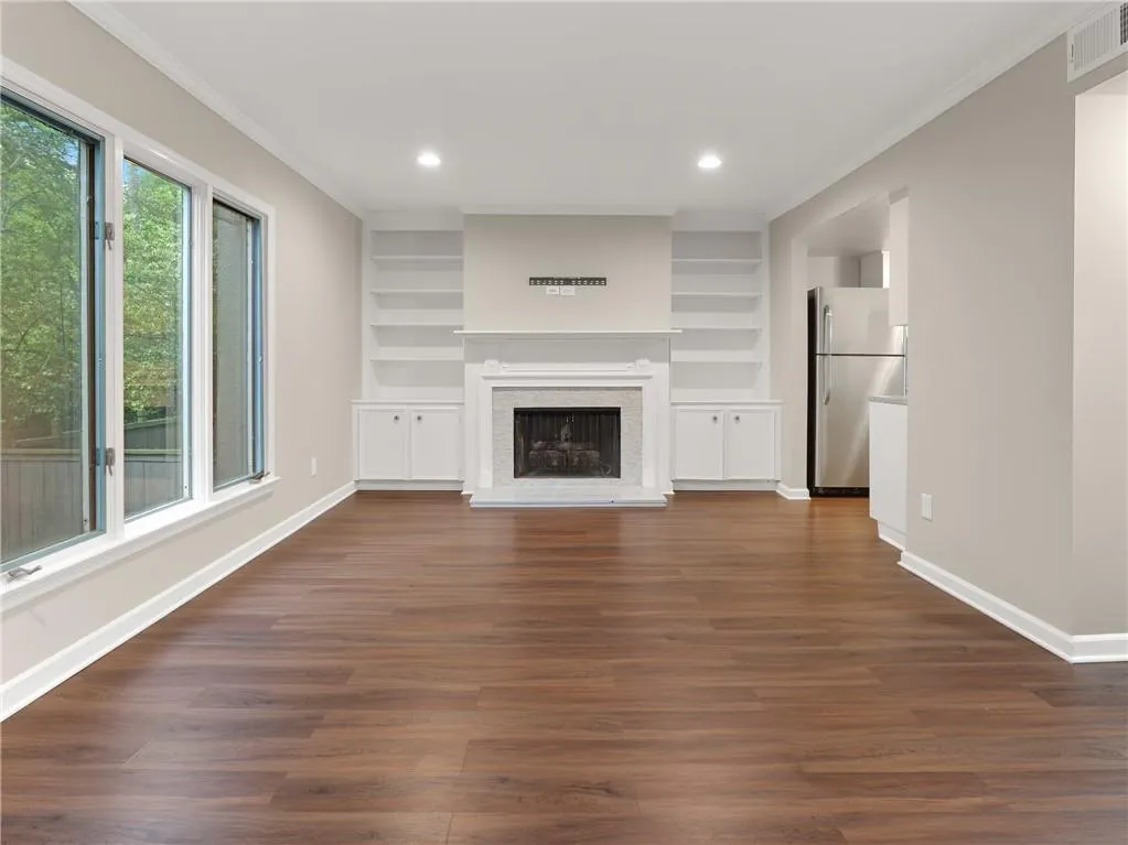 Unfurnished living room with ornamental molding, a brick fireplace, dark wood-style floors, built in features, and recessed lighting