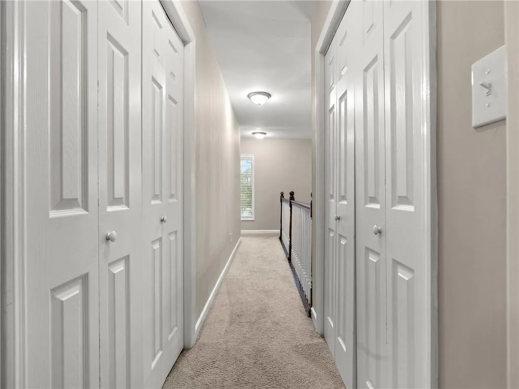 Hallway featuring light carpet and baseboards