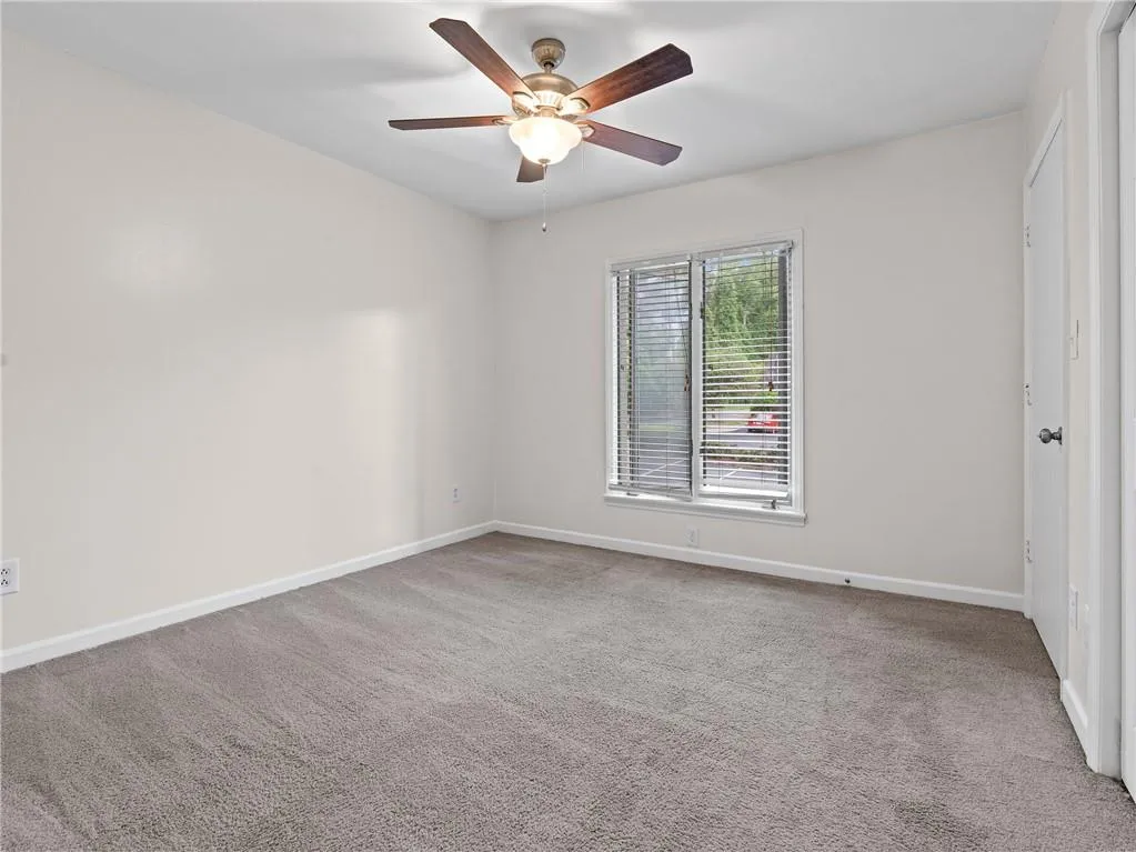 Carpeted empty room featuring ceiling fan and baseboards