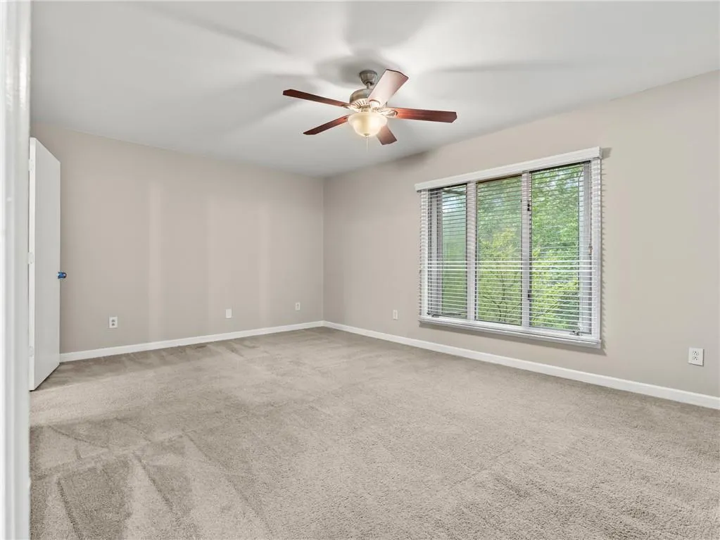 Carpeted empty room featuring baseboards and a ceiling fan