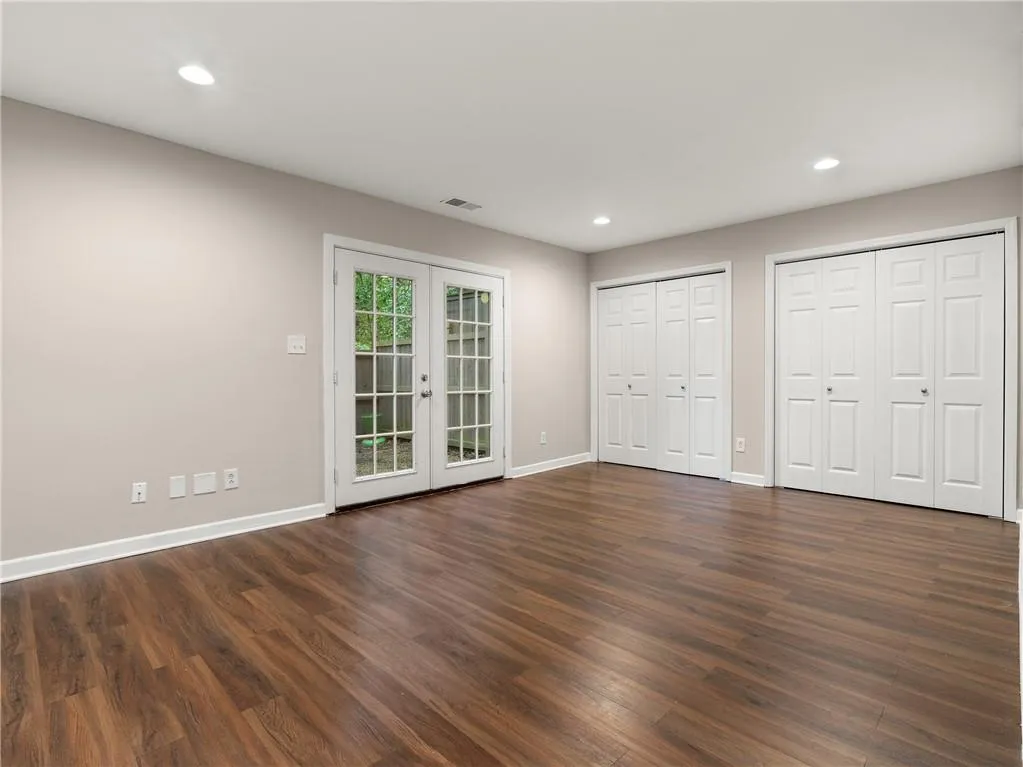 Unfurnished bedroom with recessed lighting, dark wood-style floors, french doors, access to outside, and multiple closets