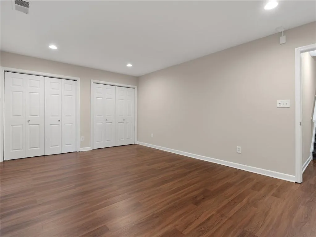 Unfurnished bedroom with recessed lighting, dark wood-style floors, and multiple closets