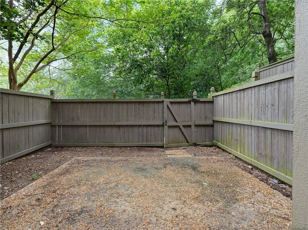 Fenced backyard with a gate and view of wooded area