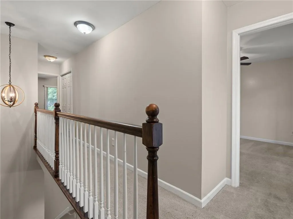 Hall with carpet, an upstairs landing, and a chandelier