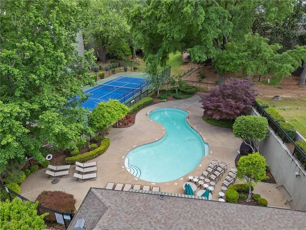 Community pool featuring a patio and view of wooded area
