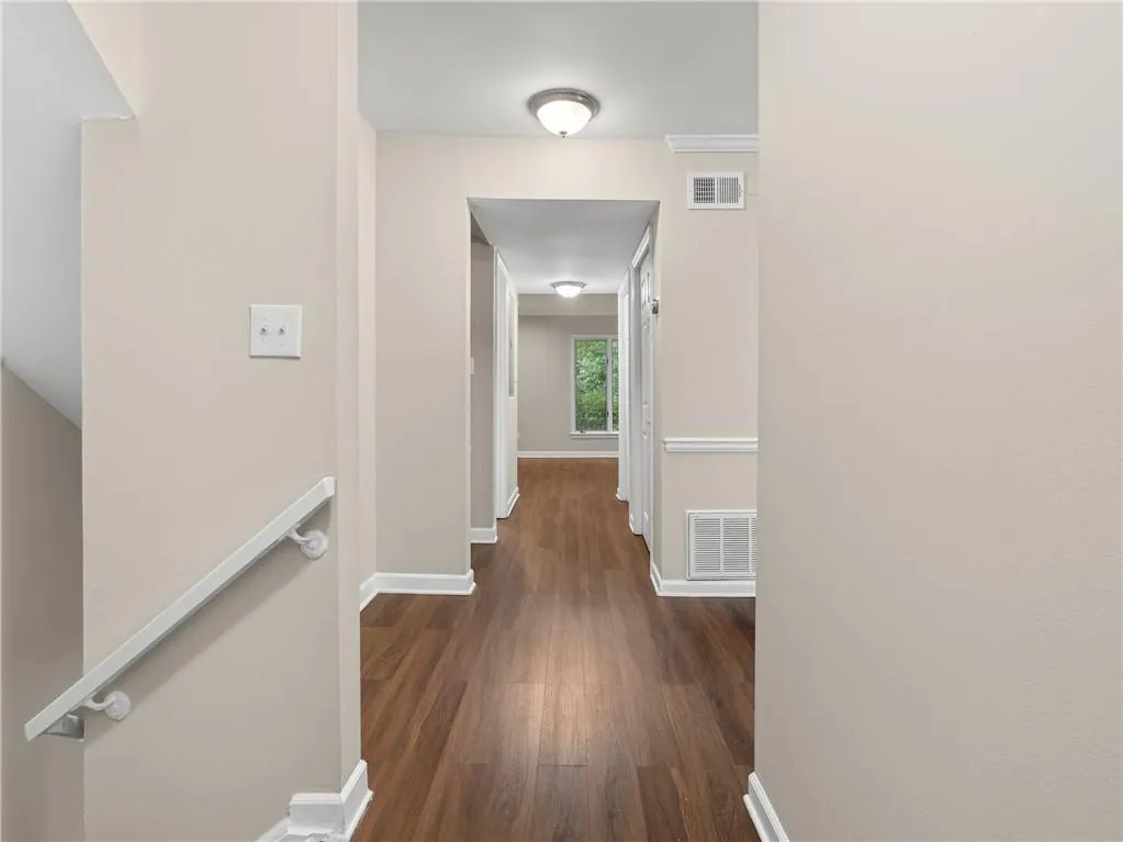 Corridor featuring an upstairs landing and dark wood-style floors