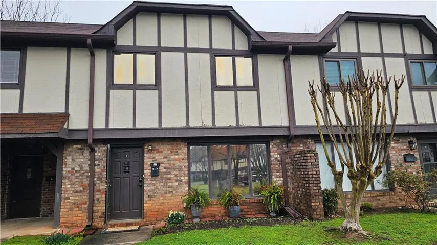 View of front of house featuring brick siding, roof with shingles, stucco siding, and board and batten siding