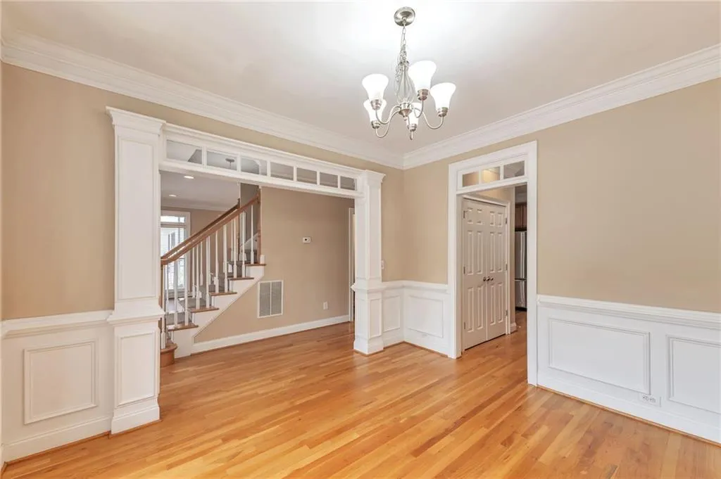 Spare room with ornate columns, ornamental molding, a decorative wall, wainscoting, and light wood-style floors