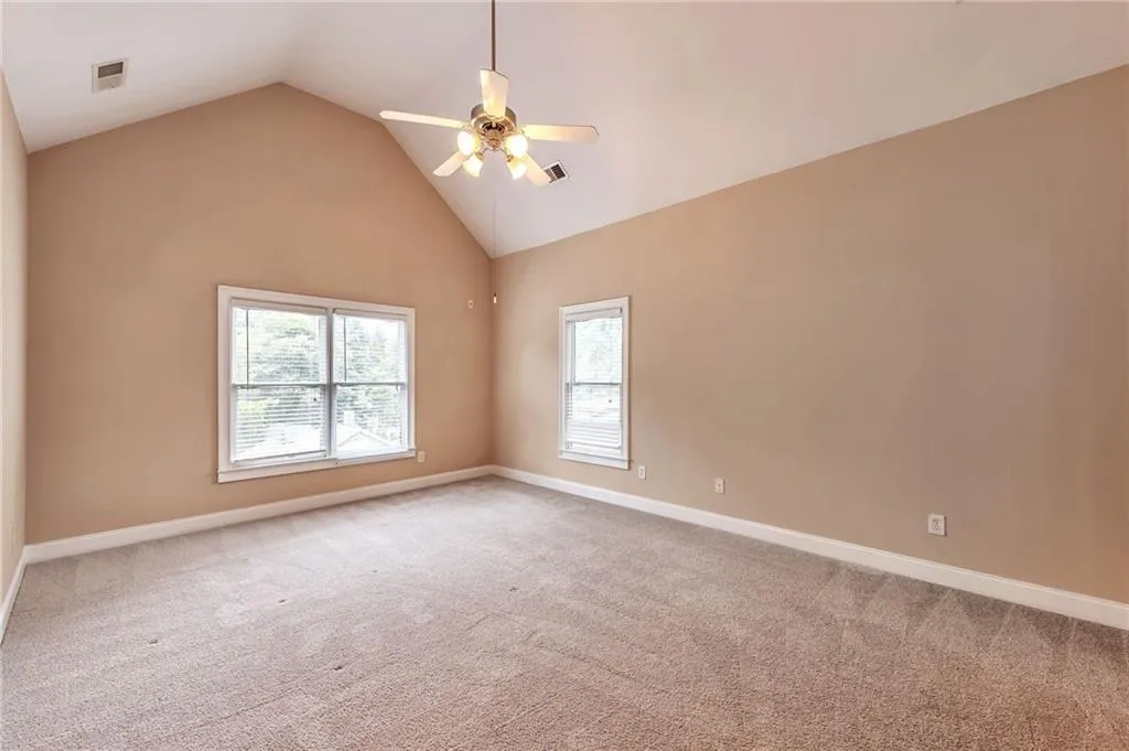 Spare room with high vaulted ceiling, light carpet, and ceiling fan