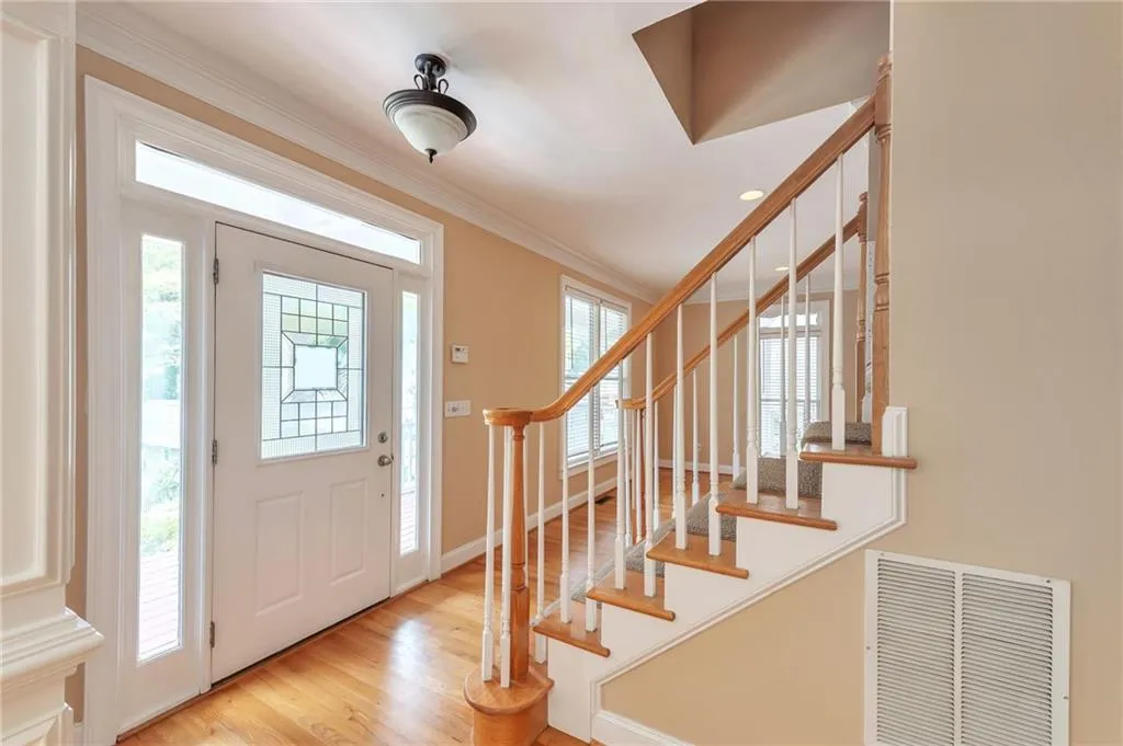 Entrance foyer with ornamental molding, light wood-type flooring, and stairway