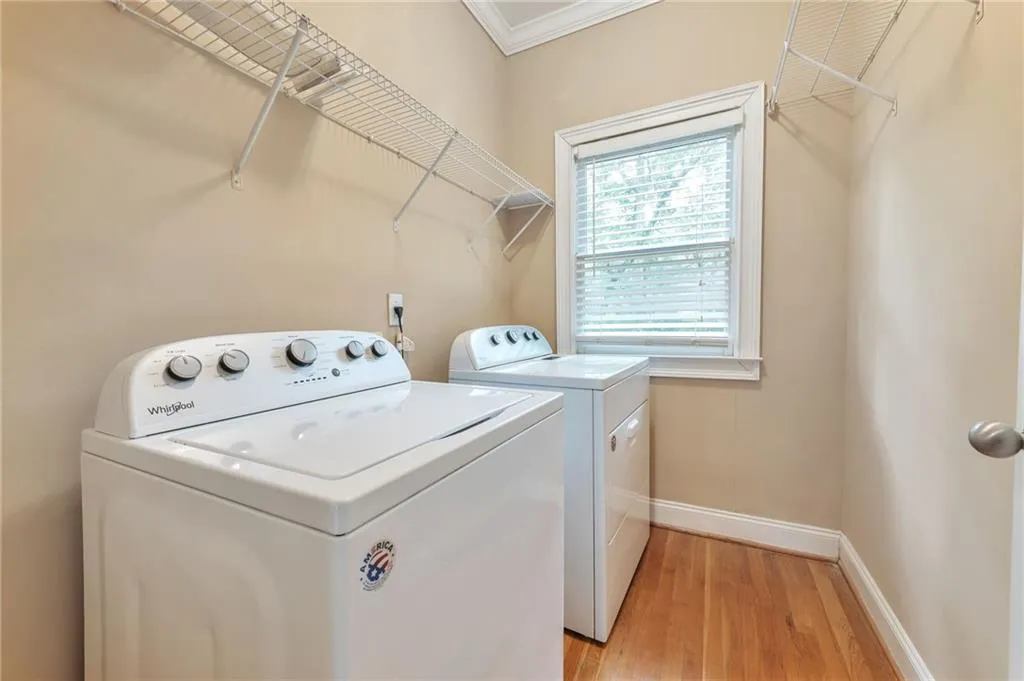 Laundry room featuring ornamental molding, light wood-style floors, and washer and dryer