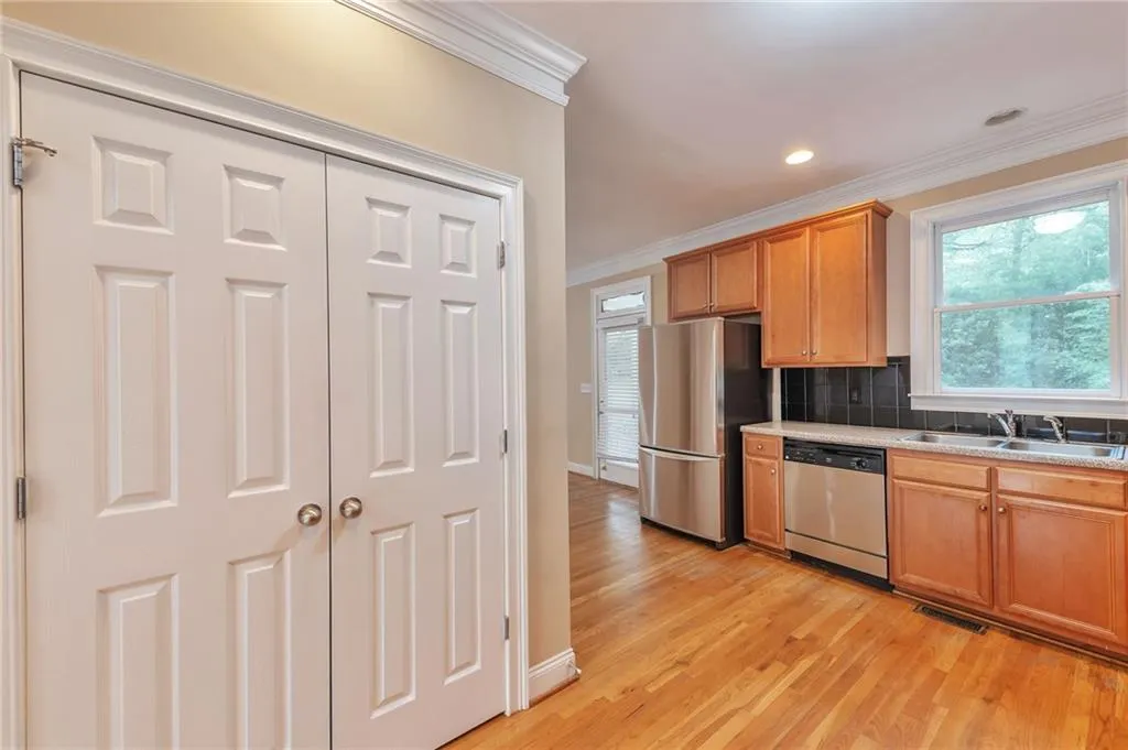 Kitchen with ornamental molding, stainless steel appliances, decorative backsplash, light wood finished floors, and brown cabinetry