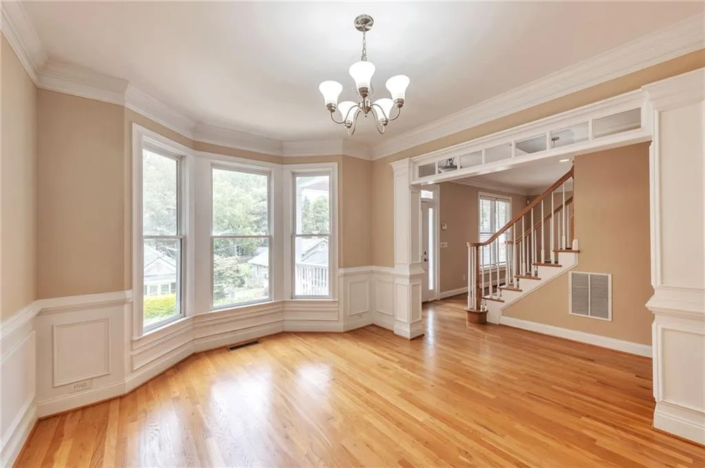 Unfurnished dining area with crown molding, stairway, light wood-style flooring, a chandelier, and a decorative wall