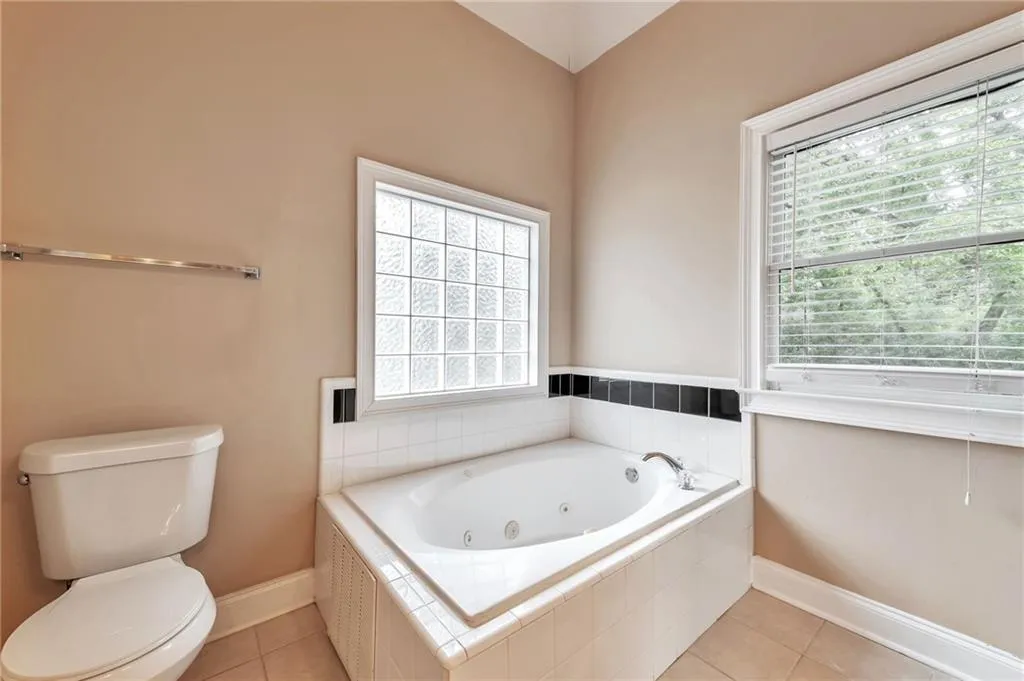 Bathroom featuring a tub with jets, light tile patterned flooring, and plenty of natural light