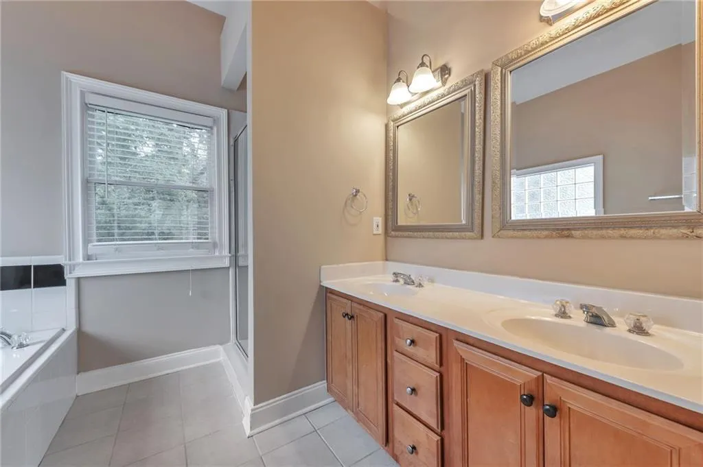 Full bathroom featuring double vanity, a bath, light tile patterned flooring, and a stall shower