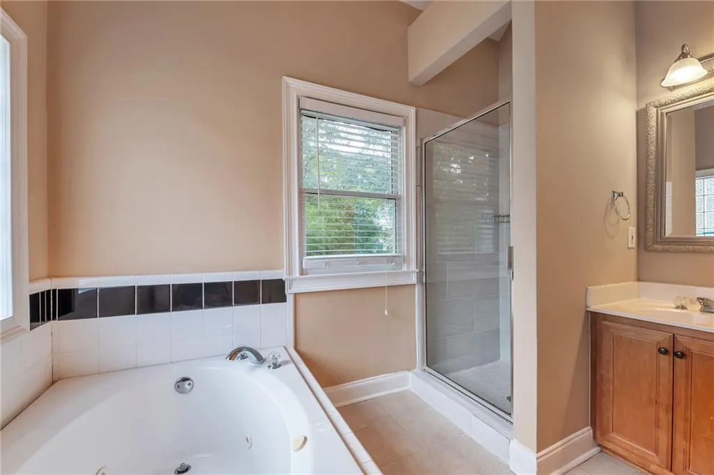 Full bath with vanity, a whirlpool tub, light tile patterned floors, and a shower stall
