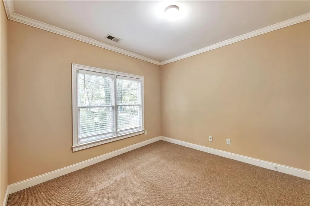 Empty room with crown molding and carpet floors