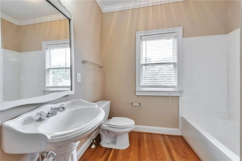 Bathroom with light wood-style flooring, plenty of natural light, ornamental molding, and  shower combination