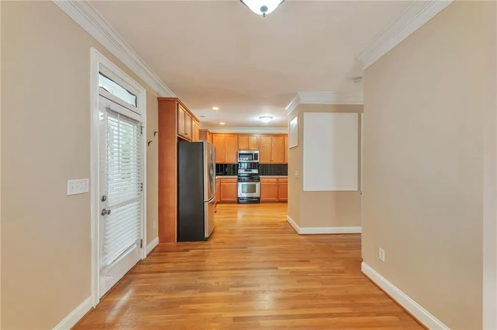 Kitchen with stainless steel appliances, light wood finished floors, backsplash, ornamental molding, and light countertops