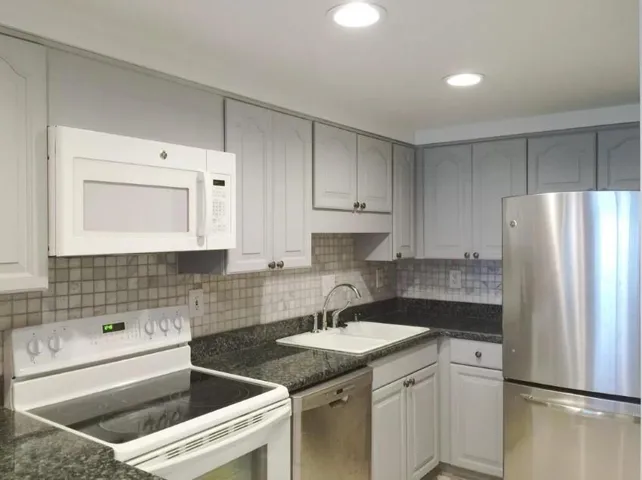 Kitchen featuring white cabinets, tasteful backsplash, appliances with stainless steel finishes, and sink