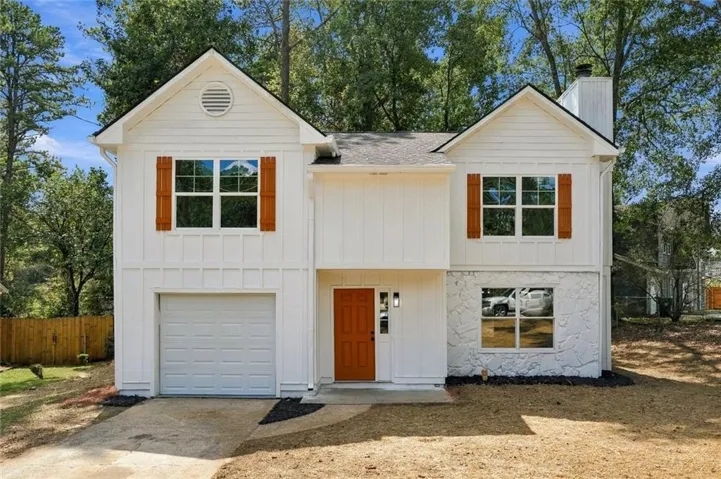 White vertical siding, stone veneer accents, natural wood-finish shutters, single-car garage, and a wood-finish front door