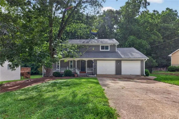 Two-story exterior with a covered front porch featuring white railings, an attached two-car garage, and a concrete driveway