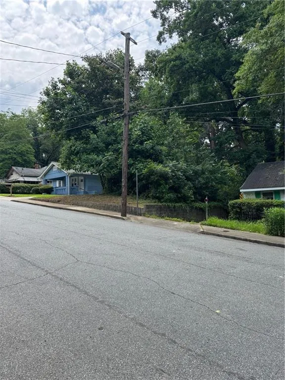 View of asphalt road featuring curbs and street lighting