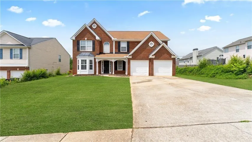 Traditional-style home featuring brick siding, driveway, a front yard, and covered porch