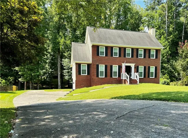 Brick two-story colonial residence with a gabled roofline and multiple windows