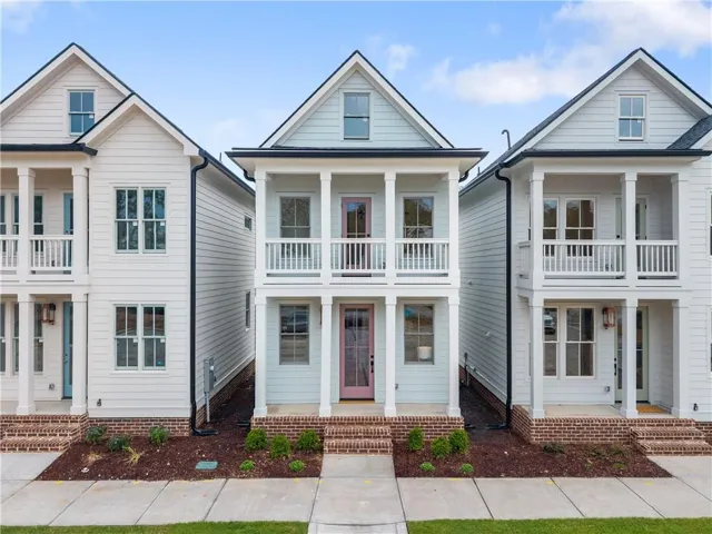 Light blue siding exterior featuring a covered porch, upper balcony, and a pink front door
