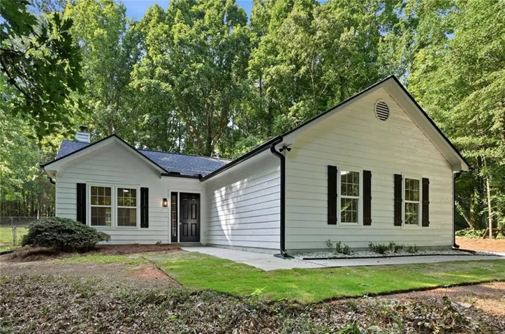 White horizontal siding exterior with dark shutters, dark trim, a dark front door, and a dark shingle roof