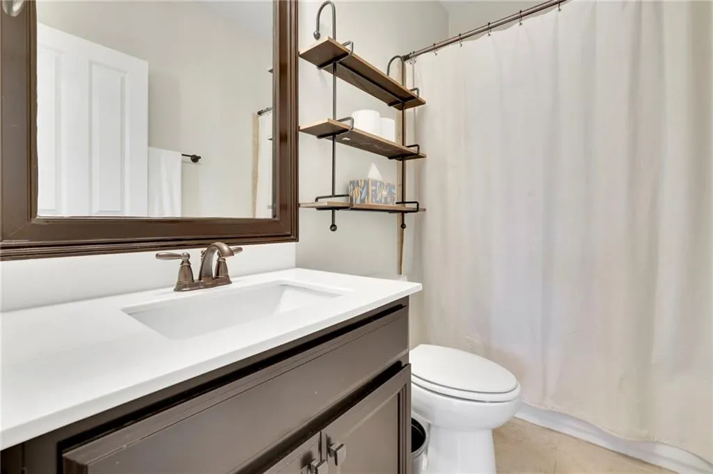Bathroom featuring toilet, vanity, and curtained shower Bathroom featuring toilet, vanity, and curtained shower