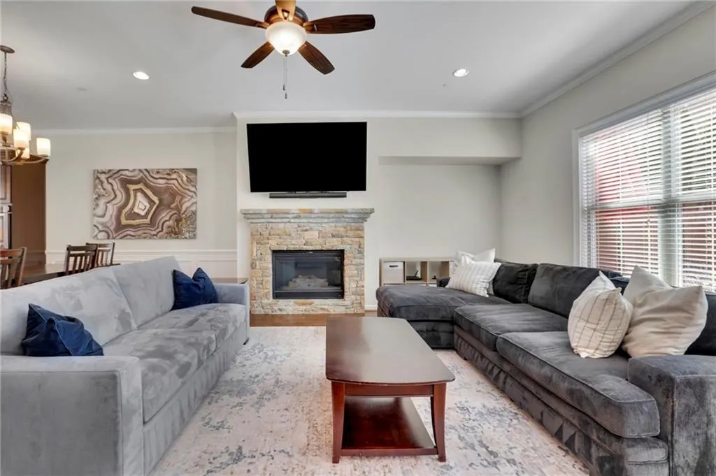 Living room featuring a fireplace, recessed lighting, crown molding, and ceiling fan with notable chandelier Living room featuring a fireplace, recessed lighting, crown molding, and ceiling fan with notable chandelier