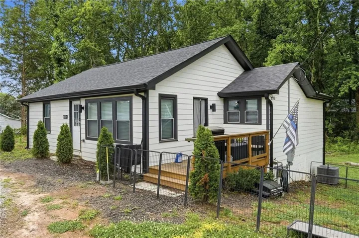 White siding exterior featuring black trim windows and a dark shingle roof