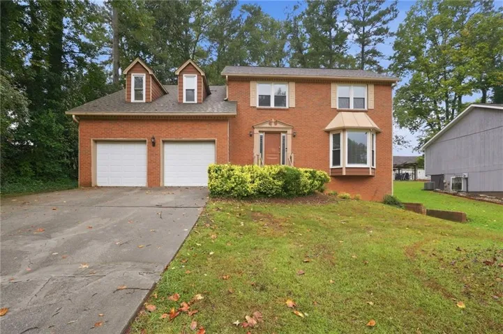 Brick exterior with a prominent bay window, two dormer windows, and an attached two-car garage