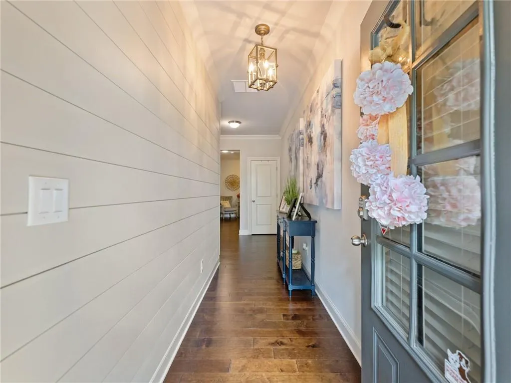 Hallway featuring a chandelier, crown molding, and dark wood finished floors