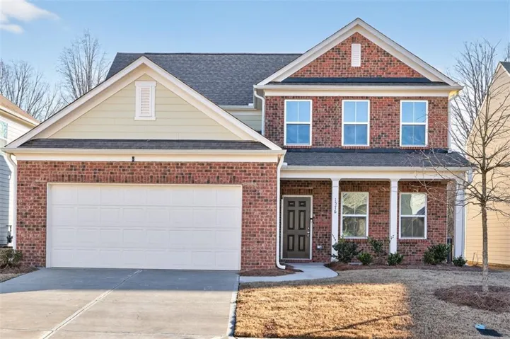 Traditional home with covered porch, driveway, brick siding, a garage, and a shingled roof