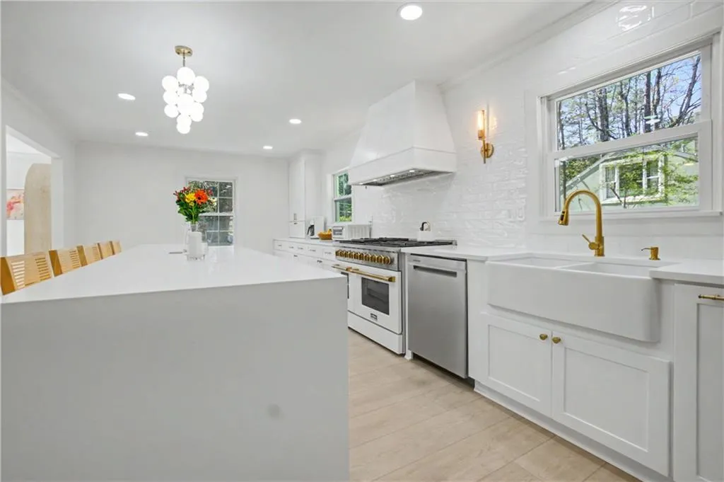 Kitchen with backsplash, high end stove, white cabinets, stainless steel dishwasher, and light stone countertops