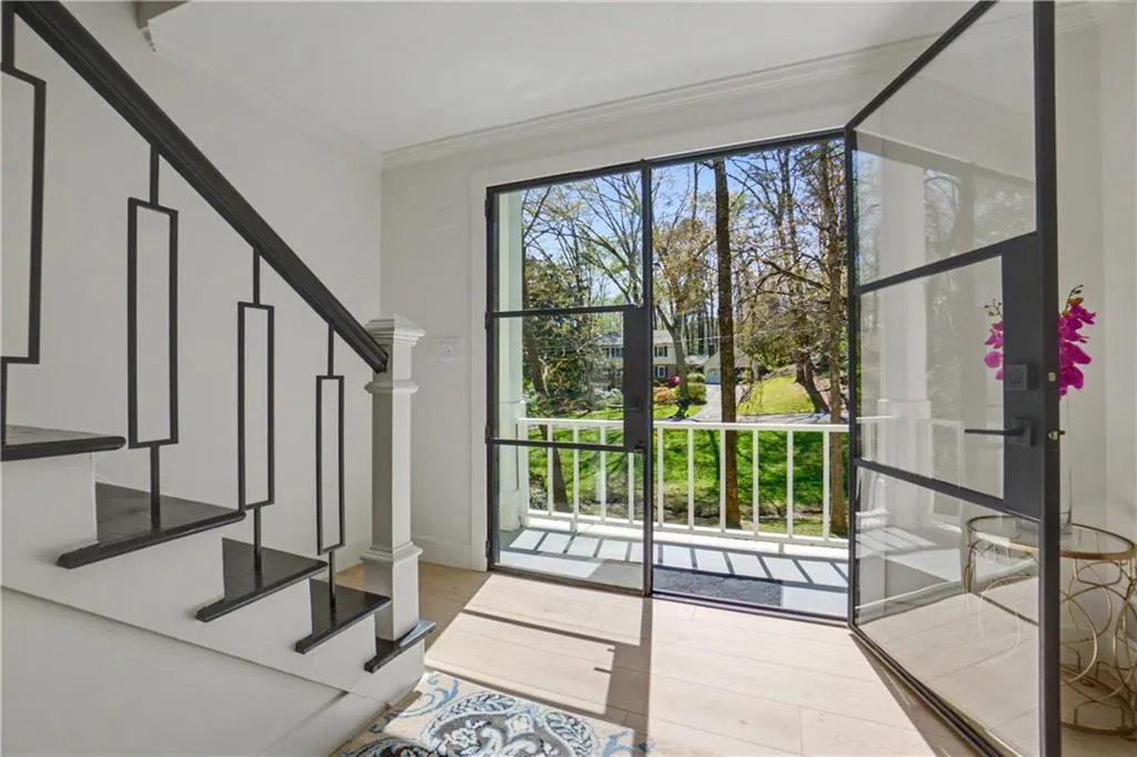 Entryway featuring custom iron doors, ornamental molding, and light wood finished floors