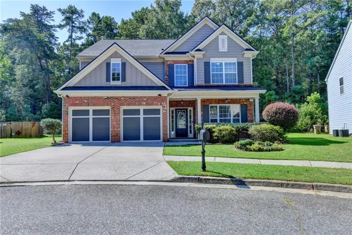 Two-story residence featuring brick and siding facade, covered front entry, two-car garage, and established landscaping