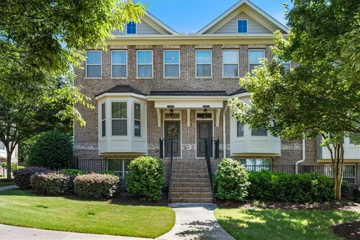 Brick exterior construction featuring gabled rooflines, bay windows, and a paved walkway leading to the entry