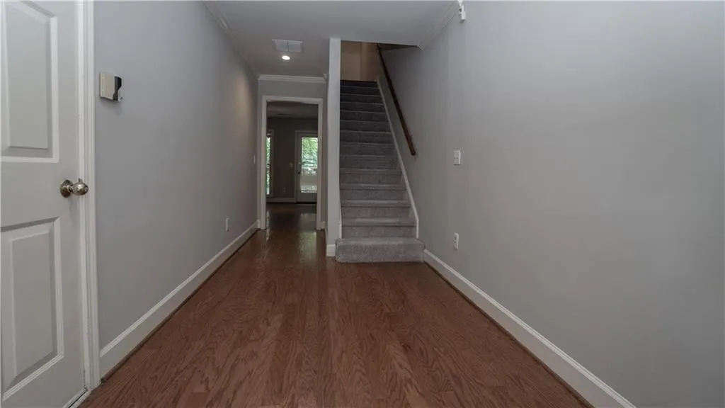 Hallway featuring ornamental molding, wood finished floors, and stairs