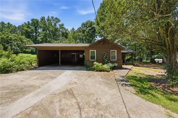 Exterior featuring a carport, concrete driveway, and mature trees