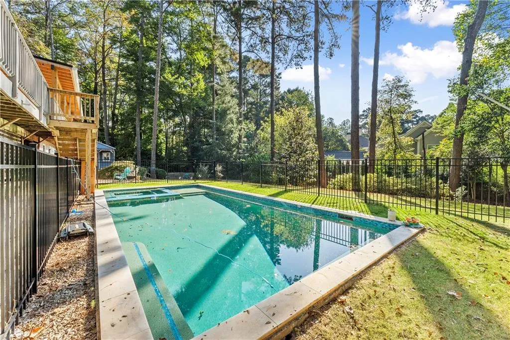 Fenced backyard featuring a playground and view of scattered trees